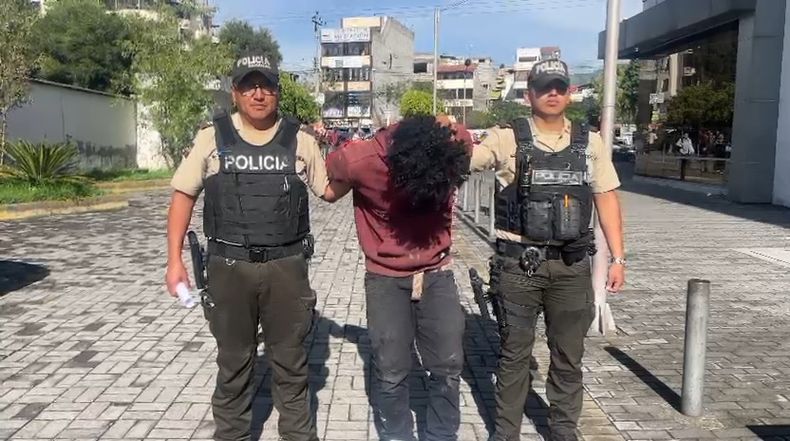 Policías custodian al hombre aprehendido por un presunto robo en una fábrica de licores de La Ferroviaria, al sur de Quito.