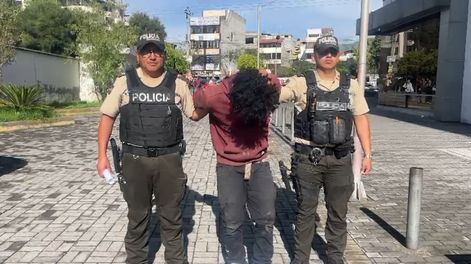 Policías custodian al hombre aprehendido por un presunto robo en una fábrica de licores de La Ferroviaria, al sur de Quito.